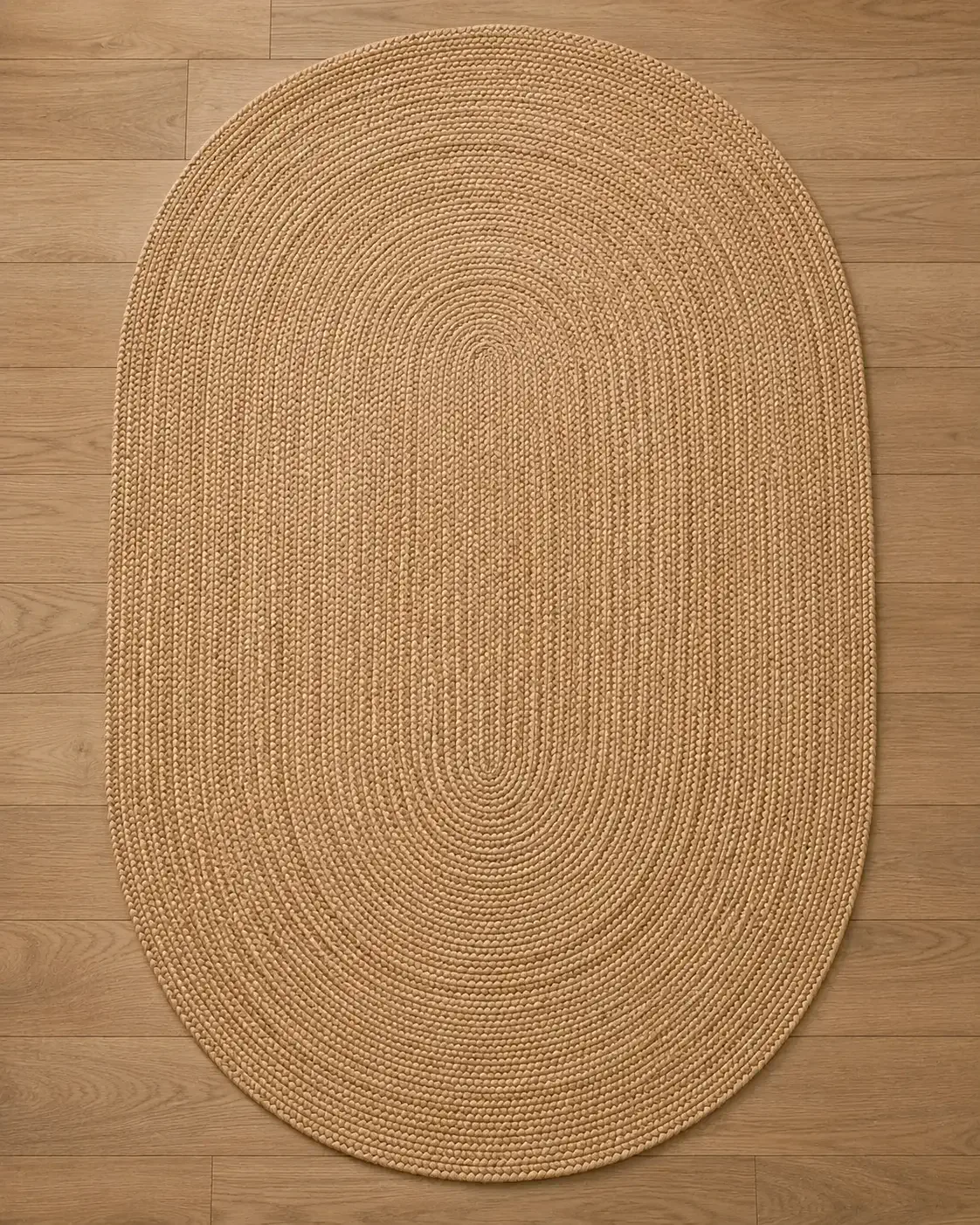 Aurelia oval hand-braided natural jute rug floor shot showcasing handcrafted braided texture in a luxury organic modern interior with oak flooring.