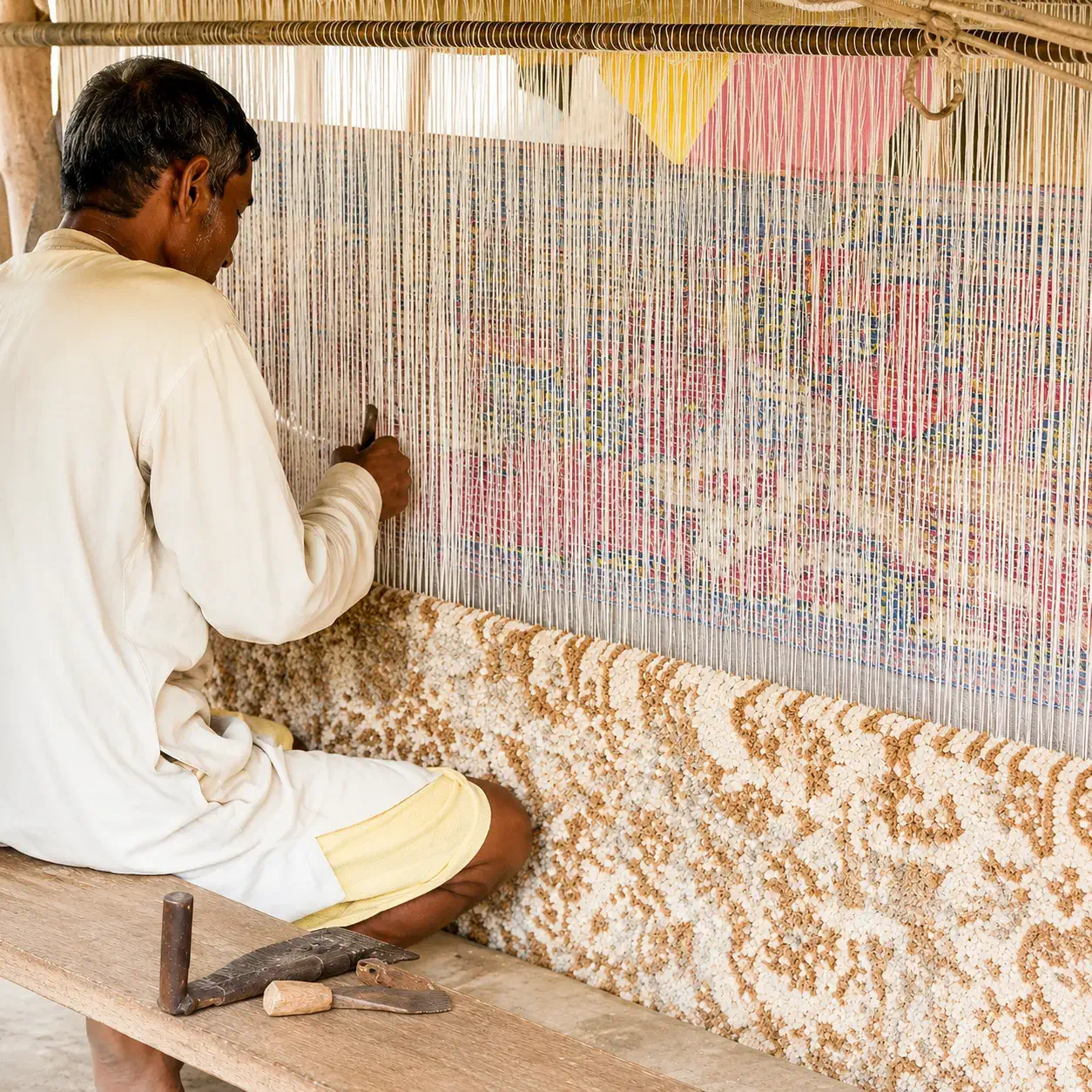 Skilled Indian artisan hand weaving a premium handmade rug on a traditional loom during the rug manufacturing process in India at Planet Arts workshop in Jaipur, Rajasthan. This hero image showcases authentic handcrafted carpet production, expert weaving techniques, precision knotting, traditional craftsmanship, sustainable rug manufacturing, and luxury handmade rug production by an experienced Indian rug manufacturer and exporter.